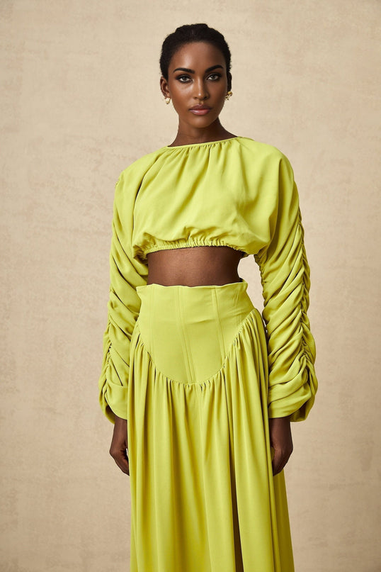 Young girl wearing a green smocked top and matching skirt set named Emilie