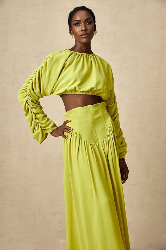 Young girl wearing a green smocked top and matching skirt set named Emilie