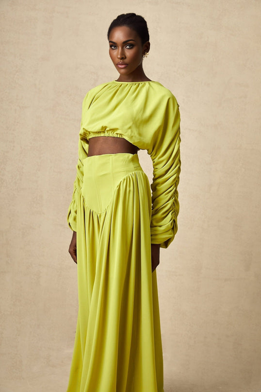 Young girl wearing a green smocked top and matching skirt set with floral pattern named Emilie