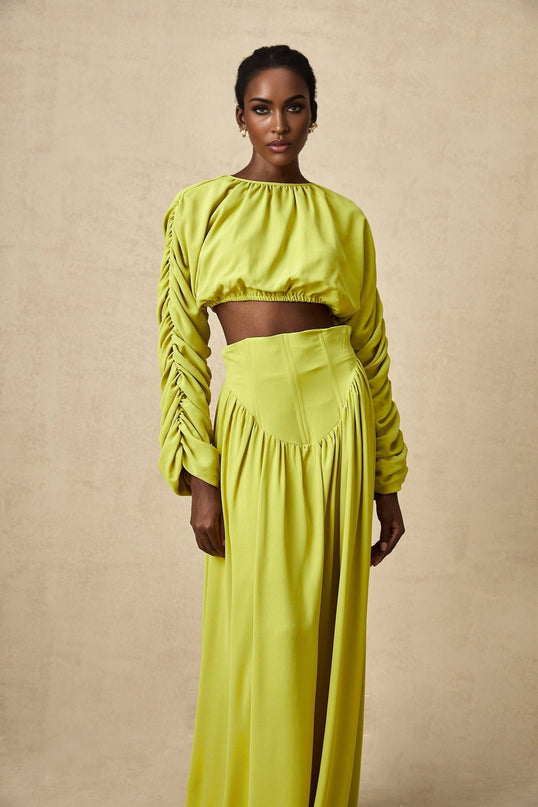 Young girl wearing a green smocked top with matching skirt set named Emilie The outfit features delicate smocking details and a coordinated design for a charming look