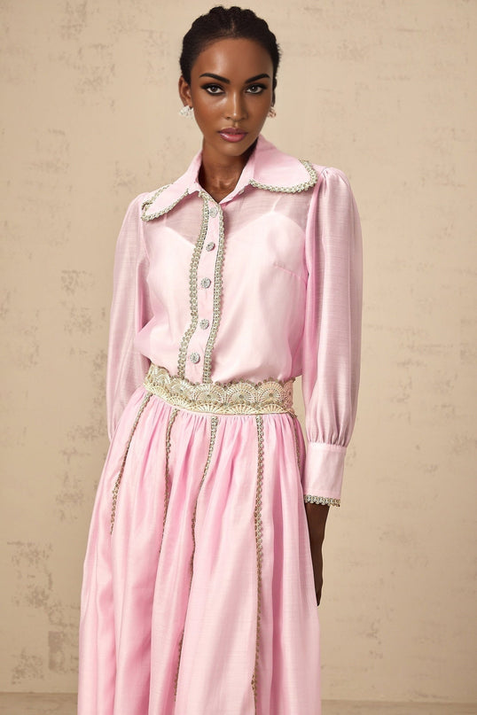 Young girl wearing a pink lace trim shirt and matching skirt set with floral details