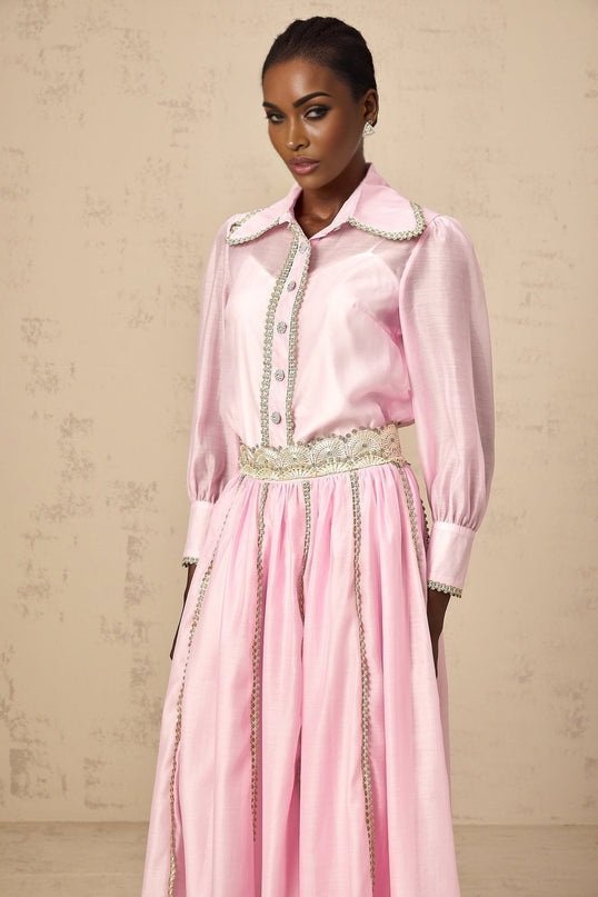 Young girl wearing a pink lace trimmed shirt and matching skirt set by Frida