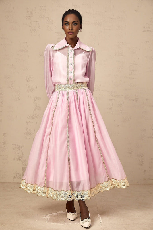 Young girl wearing pink lace trimmed shirt and matching skirt set by Frida