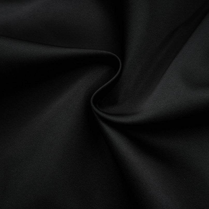 Young woman wearing a black floral lace vest over a matching dress with delicate floral patterns standing against a plain background