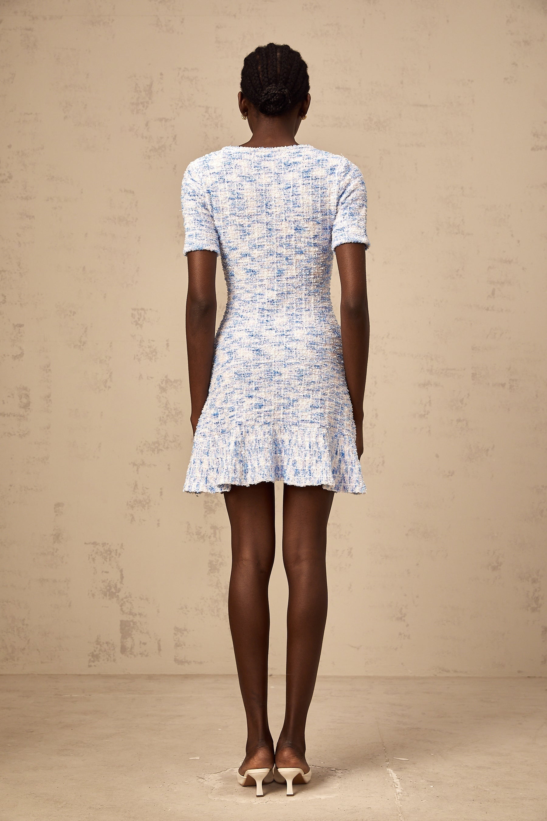 Young woman wearing a blue checked knit mini dress with short sleeves and a fitted silhouette