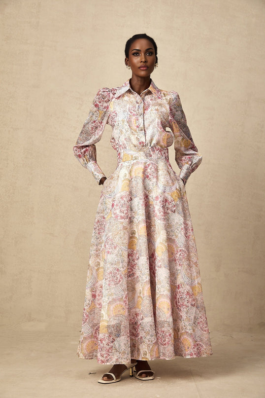 Young woman wearing a cherry pink shirt and skirt set with pattern print design standing against a plain background