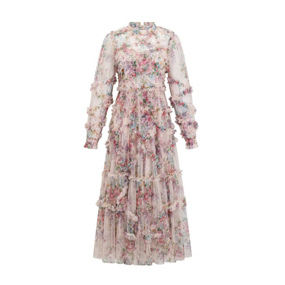 Young woman wearing a floral midi dress with ruffled tulle skirt and delicate floral pattern standing against a plain background