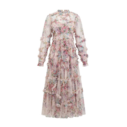 Young woman wearing a floral patterned midi dress with ruffled tulle details and a fitted bodice standing in a garden setting