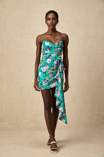 Young woman wearing a green mini dress with floral pattern and ruched detailing