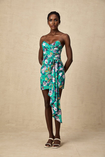 Young woman wearing a green mini dress with floral pattern and ruched detailing
