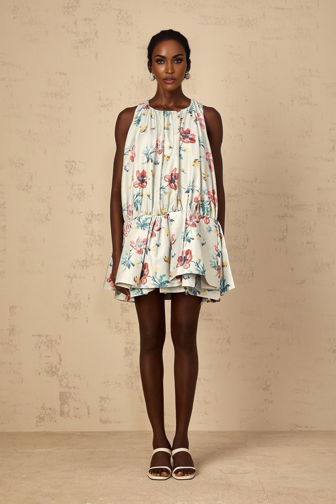 Young woman wearing a green mini dress with floral print and shirred detailing