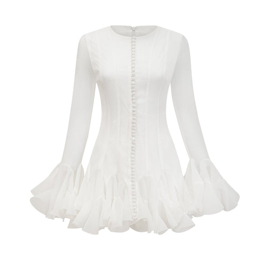 Young woman wearing a light flowy Anais mini dress with flared skirt and semi sheer fabric standing in casual pose