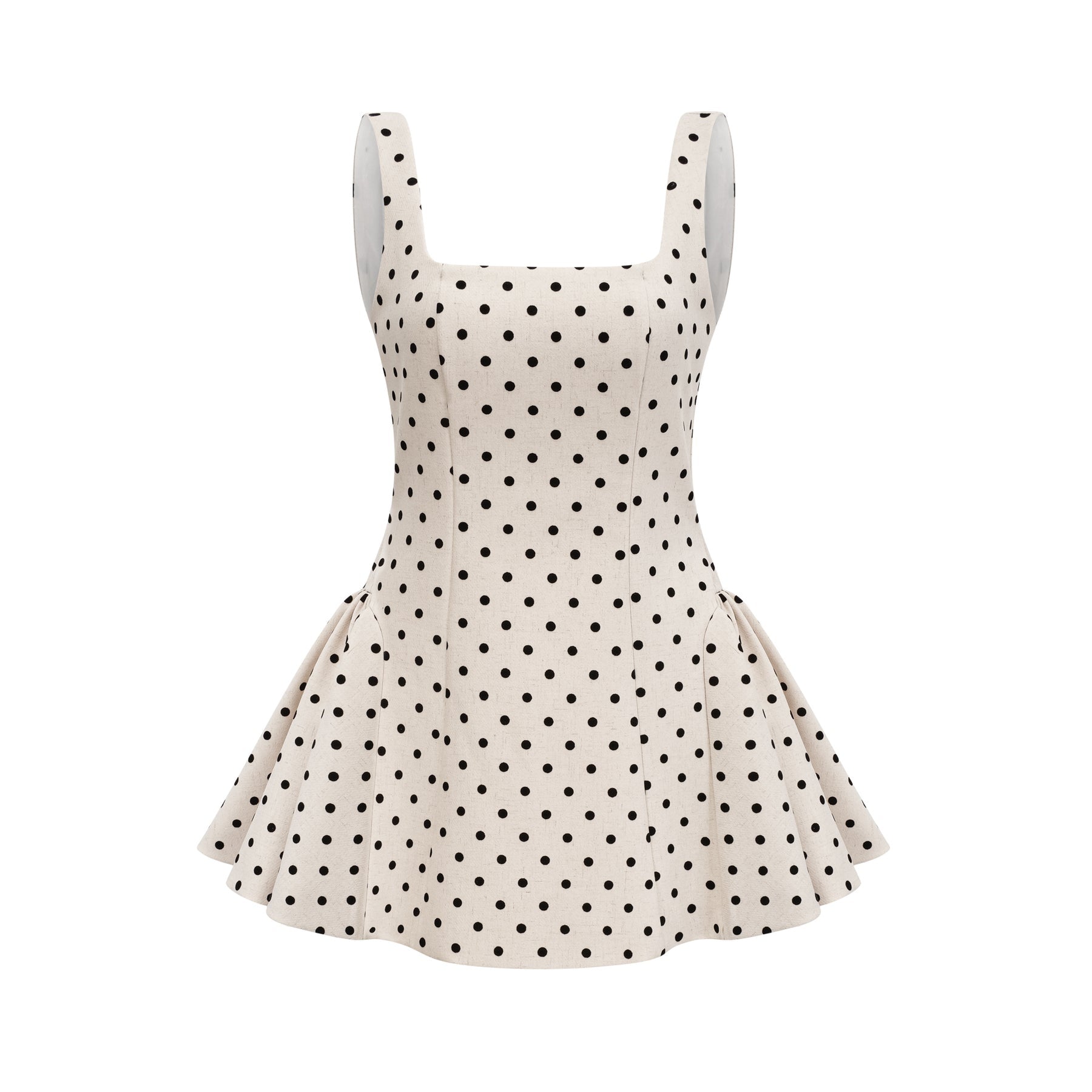 Young woman wearing a neutral colored polka dot mini dress with puff sleeves and a fitted waist standing against a plain background