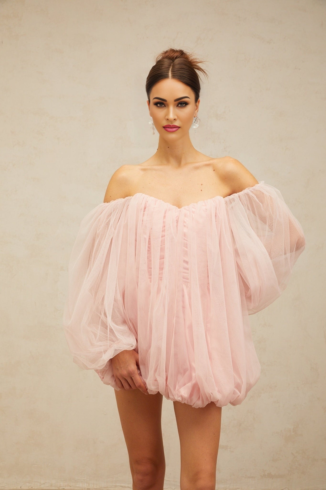 Young woman wearing a pink layered tulle mini dress with bubble skirt and sleeveless design