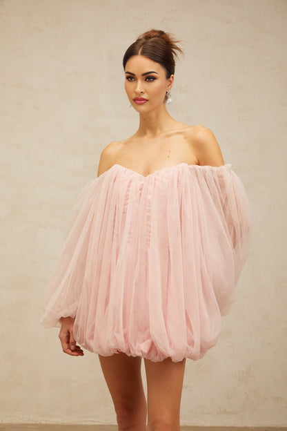 Young woman wearing a pink mini dress with layered bubble tulle skirt standing in a casual pose