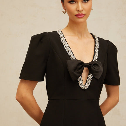 Young woman wearing a short black dress with a large bow detail