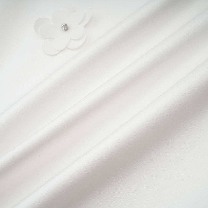 Young woman wearing a short floral print dress with puff sleeves and a fitted waist standing against a plain background