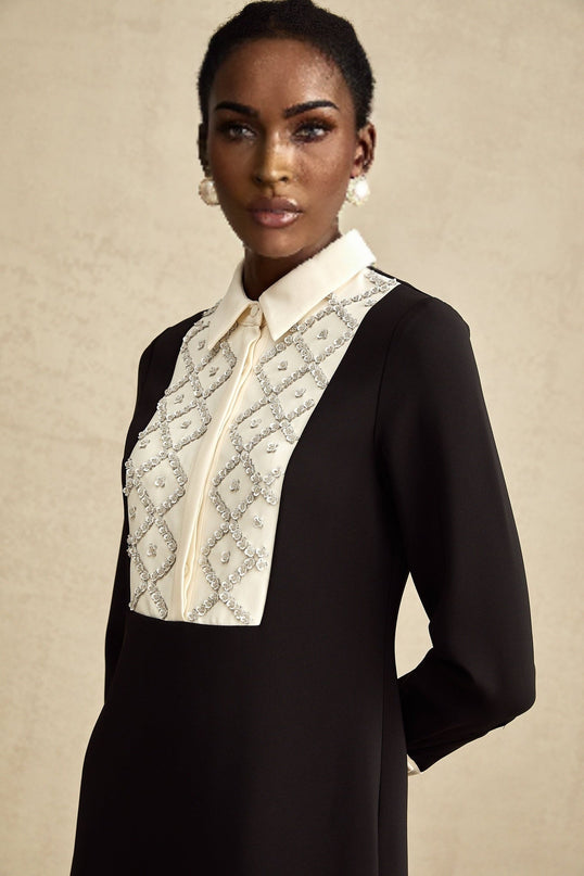 Young woman wearing a short mini dress with contrasting colors and embellishments standing in a stylish pose