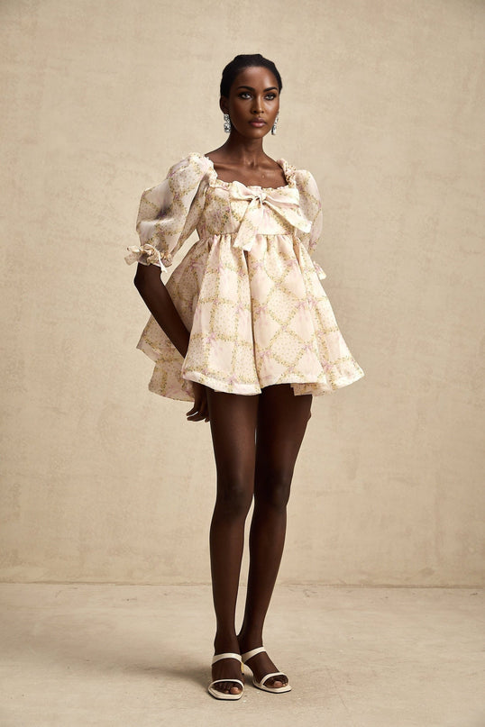 Young woman wearing a short puffy mini dress with a check pattern and a large bow detail at the front