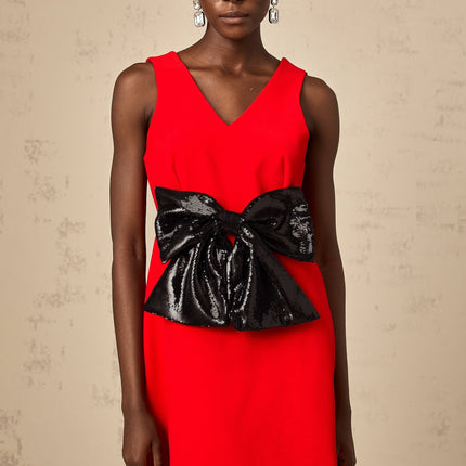 Young woman wearing a short red dress with a Vneckline and sequin bow detail at the waist
