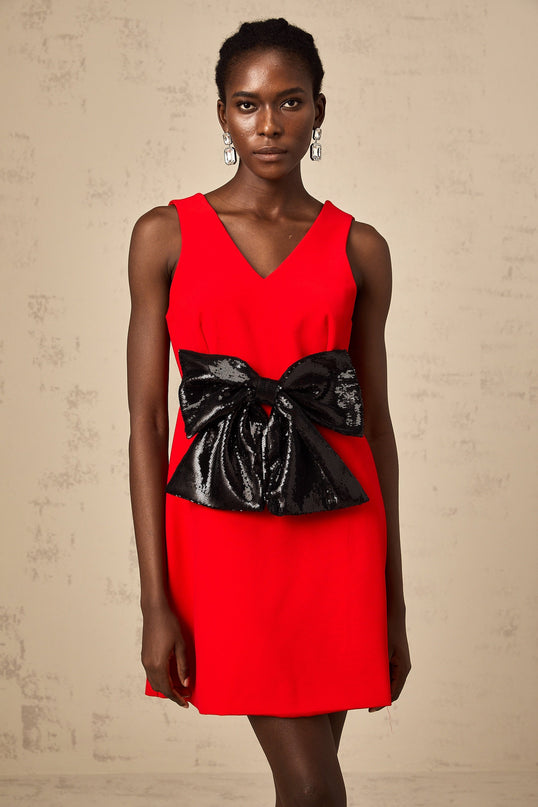 Young woman wearing a short red dress with a Vneckline and sequin bow detail at the waist