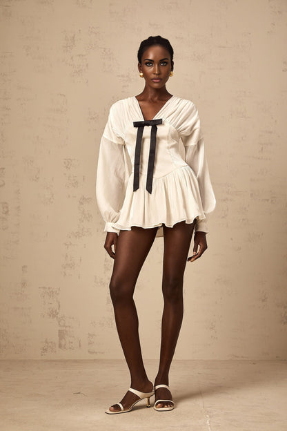Young woman wearing a short white dress with a bow detail and glitter accents