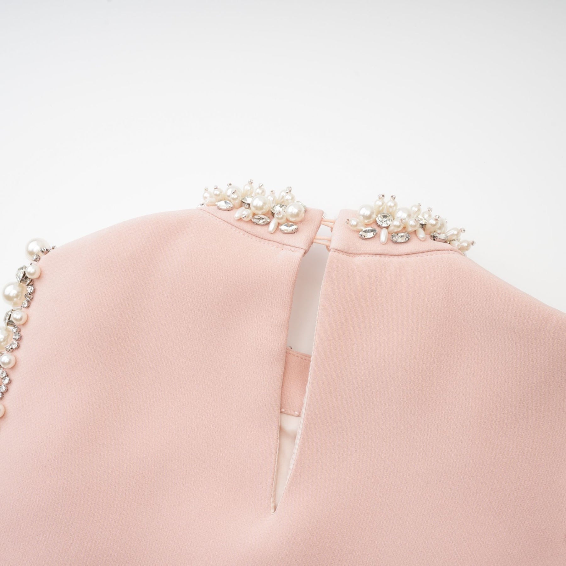 Pink sleeveless dress with round neckline crystal and faux pearl embellishments button fastening at the back and thighlength hemline Made of 80% Polyester and 20% Cotton
