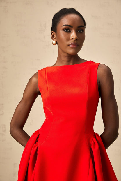 Young woman wearing a vibrant red sleeveless mini dress with a flared skirt standing against a plain background