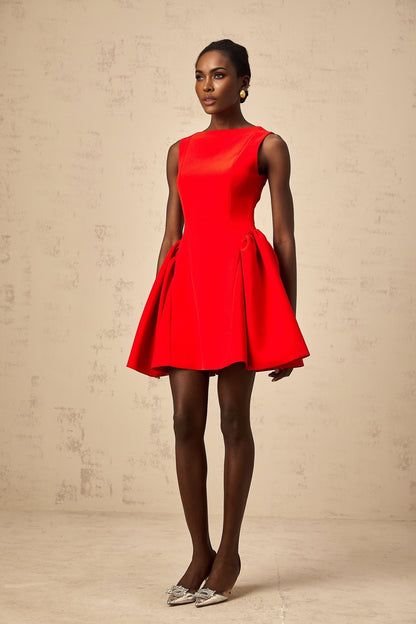 Young woman wearing a vibrant red sleeveless mini dress with a flared skirt standing against a plain background