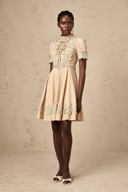 Young woman wearing a white flared mini dress with delicate corded lace pattern and short sleeves