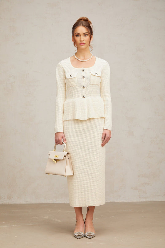 Young woman wearing a white knitted two piece outfit consisting of a sleeveless top and short skirt