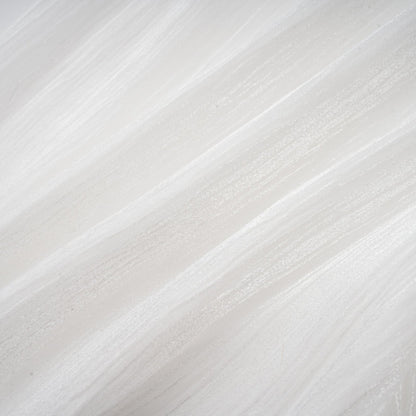 Young woman wearing a white mini dress with full pleats and cinched waist standing against plain background