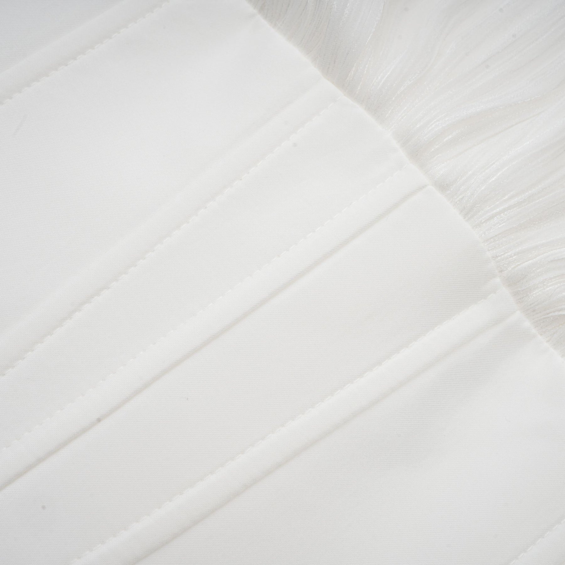 Young woman wearing a white pleated mini dress with cinched waist standing against a plain background