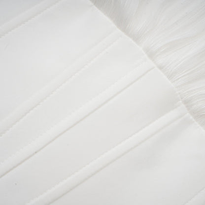 Young woman wearing a white pleated mini dress with cinched waist standing against a plain background
