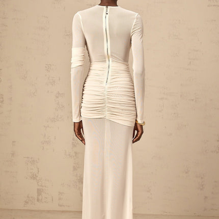 Young woman wearing a white ruched tulle maxi dress with long sleeves and a flowy skirt standing in an elegant pose