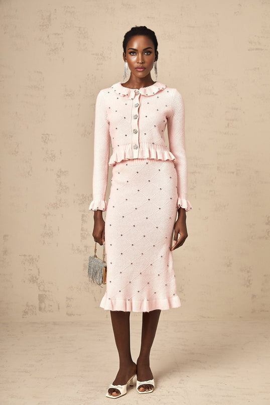 Young woman wearing pink argyle patterned knitted cardigan with matching skirt in a coordinated outfit set