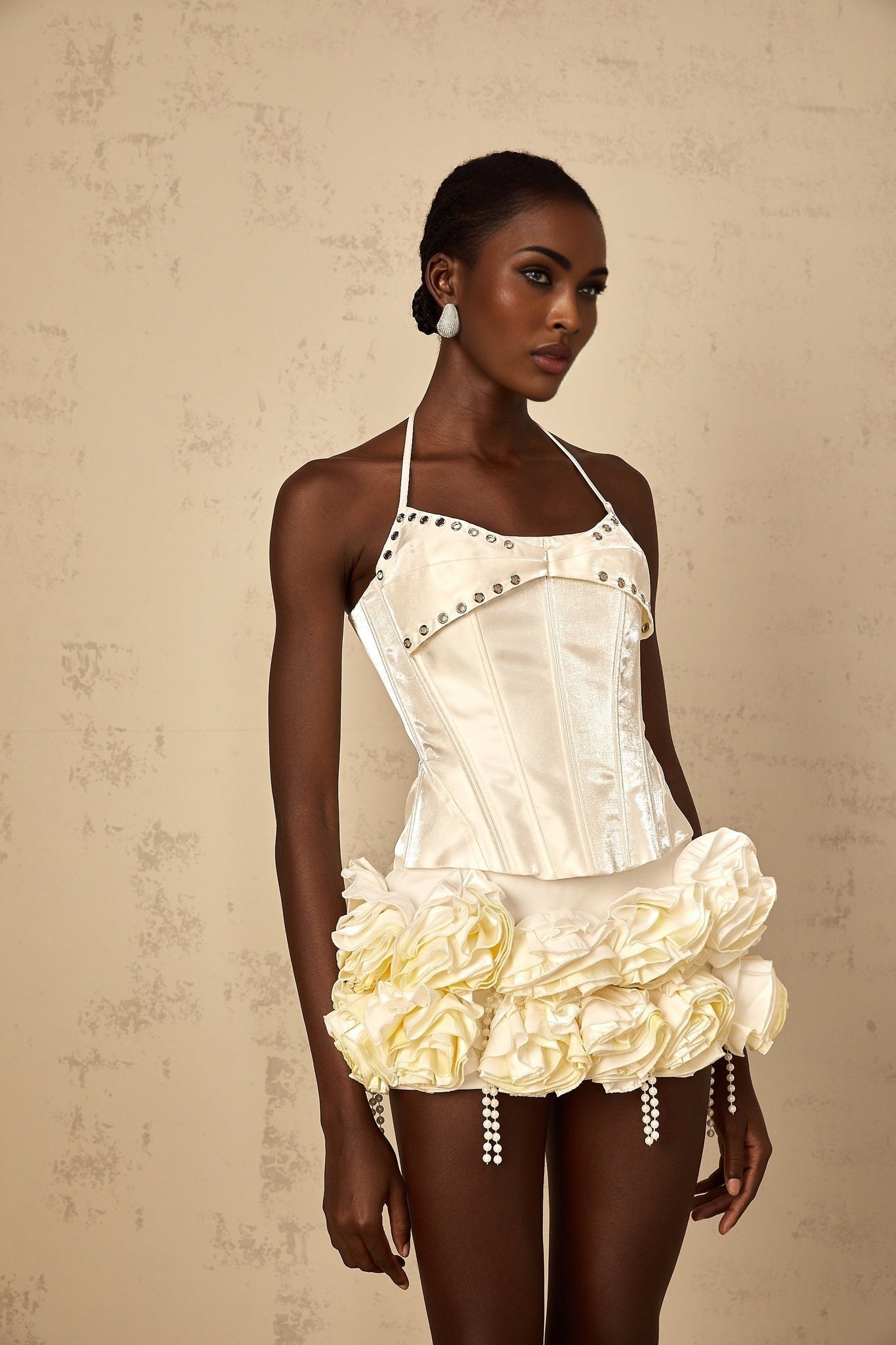 Young woman wearing white floral corset top and matching skirt set with Madeleine design standing against plain background